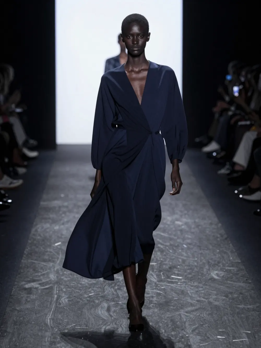 A model walking the runway, backlit